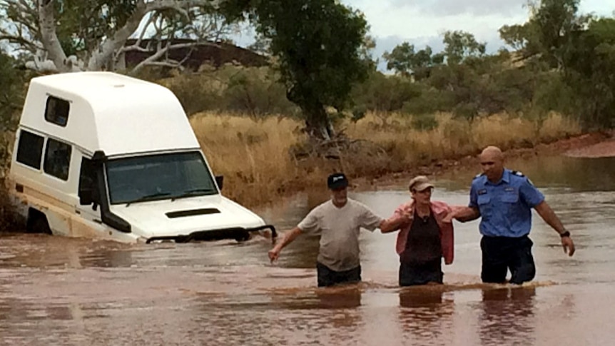 A couple are helped through floodwaters in the Pilbara by WA police. May 6, 2014.