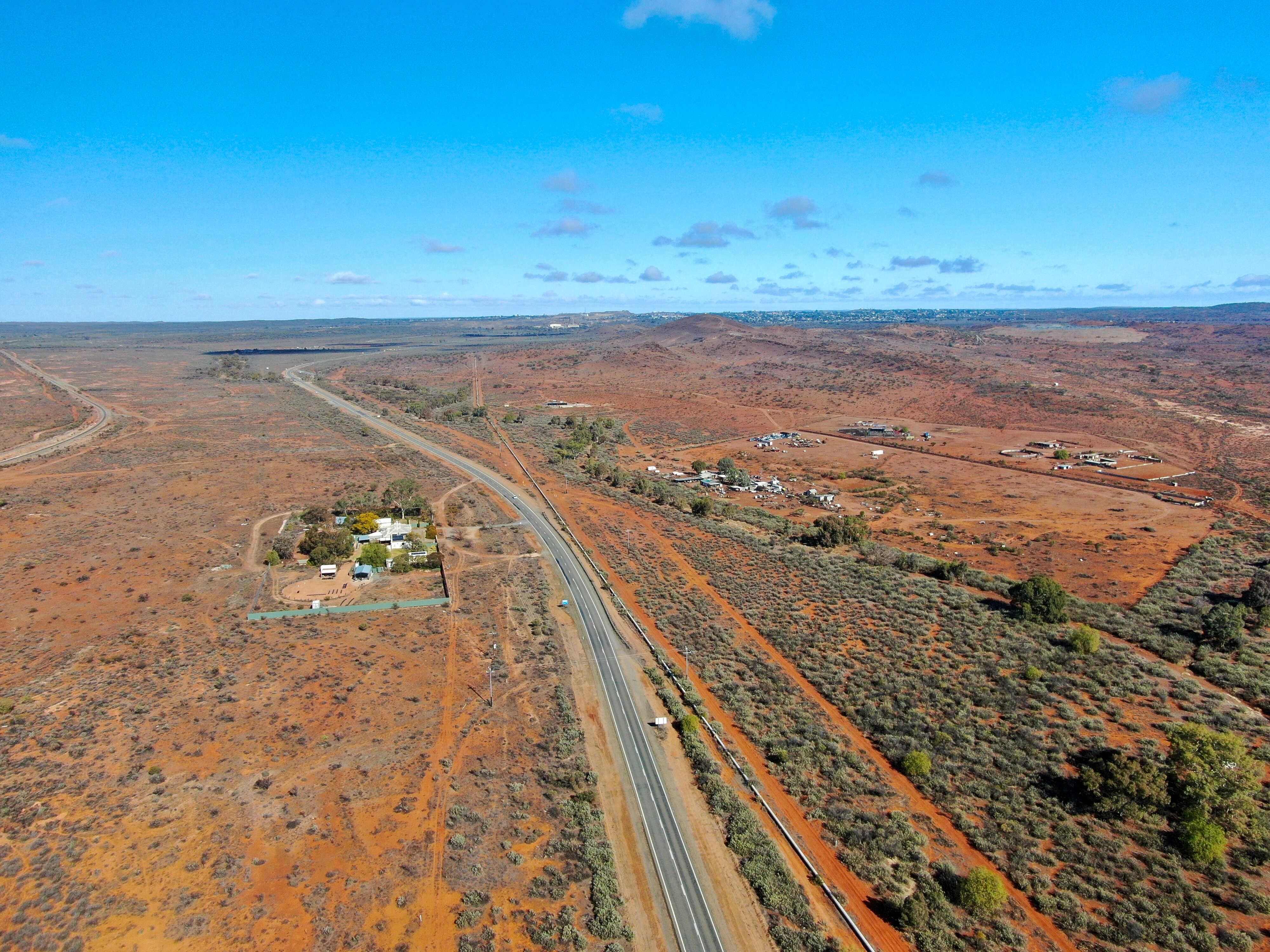 Aerial view of highway with a few residences pictured on the ground. 