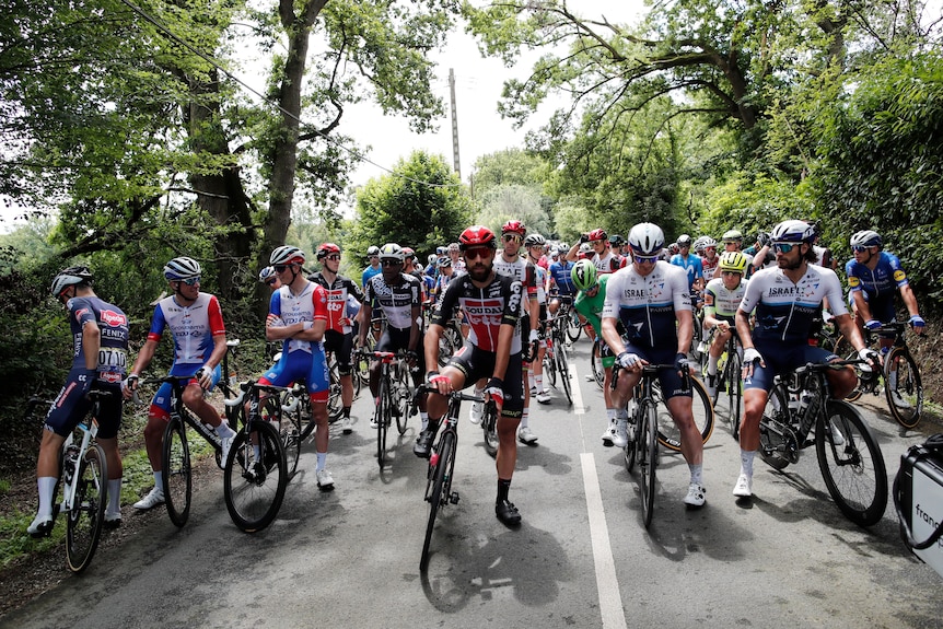 Cyclists in the Tour de France pausing on the road during a stage.