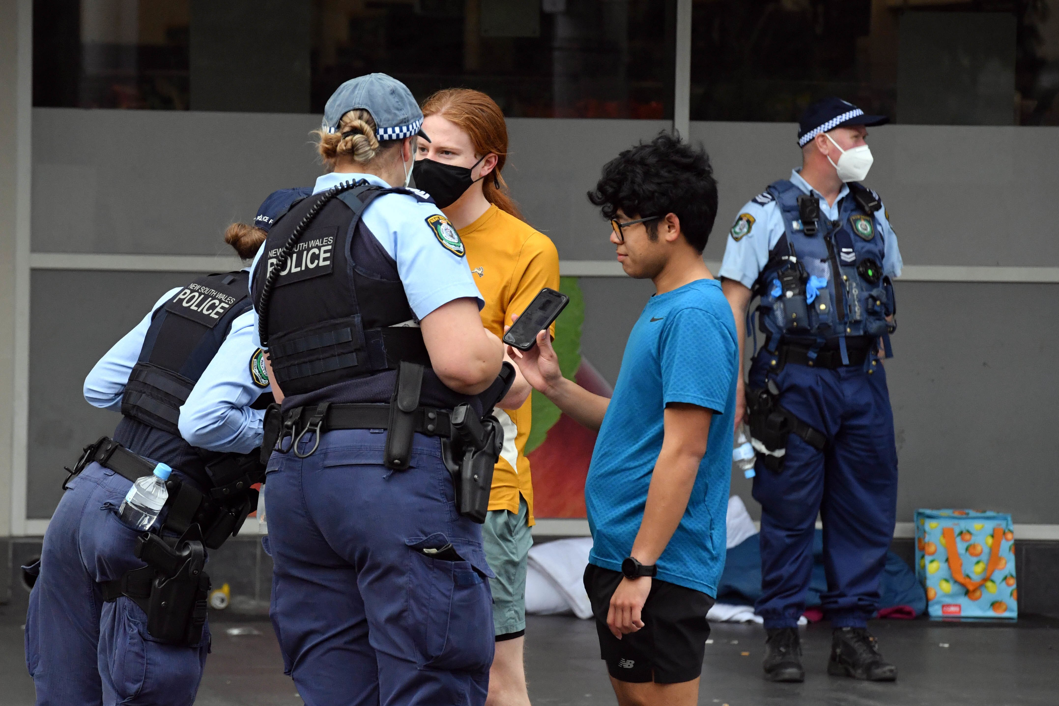 masked police officers check the identities of two young men
