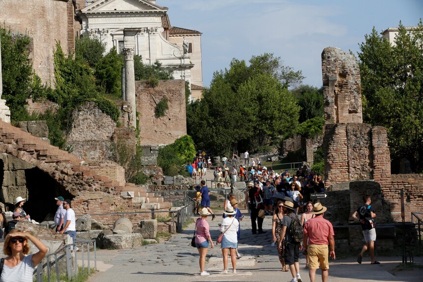 Tourists walk along the Roman Forum in Rome.