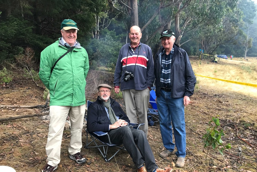 Rod Oliver and his extended family and a friend in camp chairs around a fire