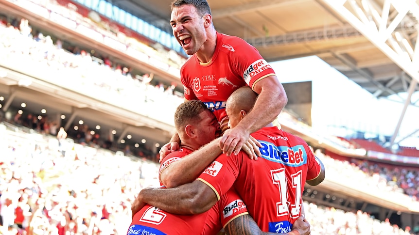 Three NRL players celebrate a try