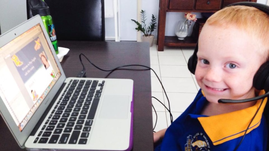 A school boy sits in front of a laptop