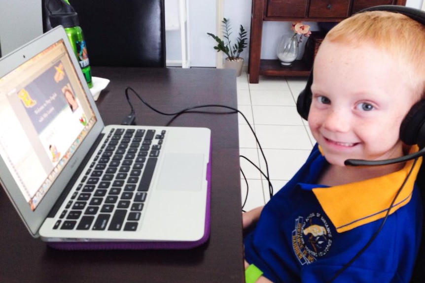 A school boy sits in front of a laptop