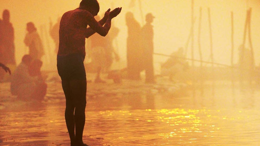 A devotee prays at sunrise on the Sangham - the confluence of the Yamuna and Ganges rivers - during the Kumbh Mela in India on January 13, 2013.