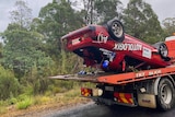 A damaged car upside down on a truck 