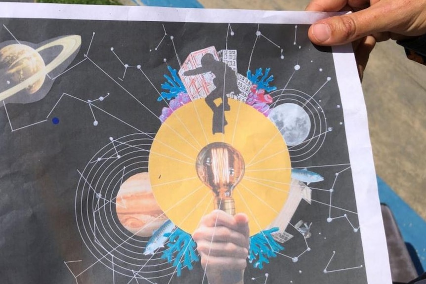 A printout of artwork for a skateramp, with planets, a skater shilloute and a hand on a black background.