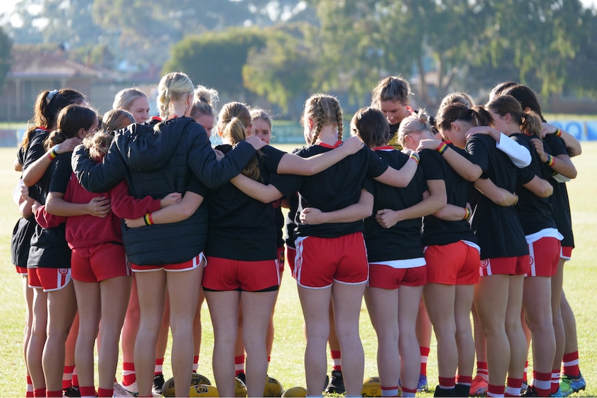 Un grupo de mujeres se apiñan en un campo de fútbol