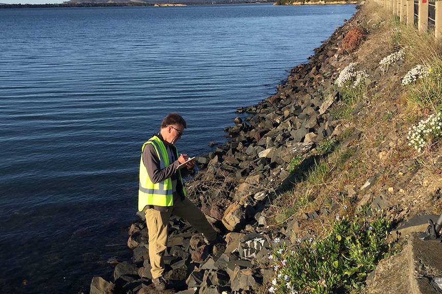 Dr Eric Woehler standing on the bank of the Sorell Causeway with a clipboard.