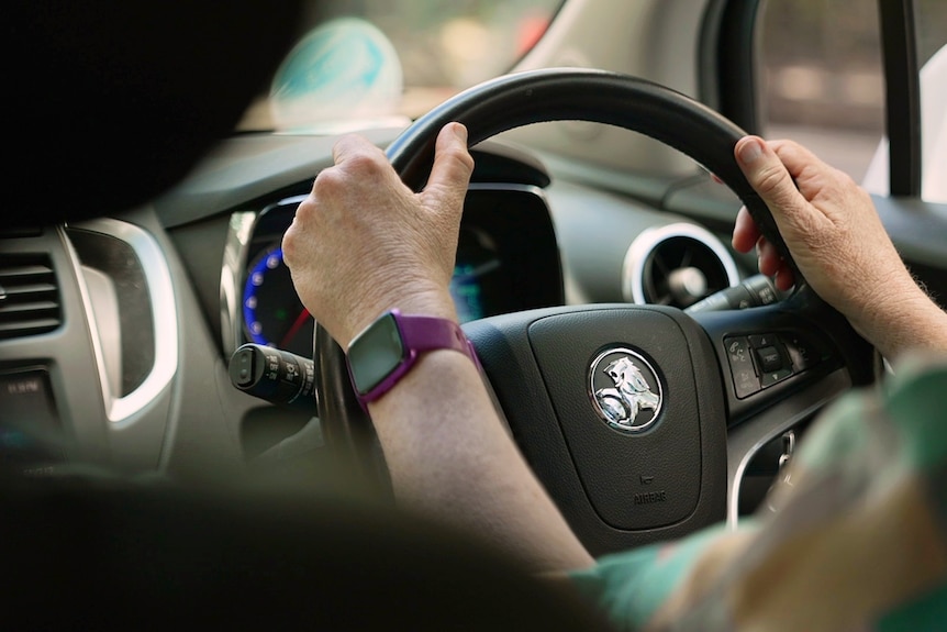 Glenys Petrie's hands on a steering wheel