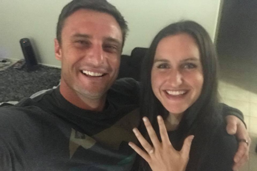 A man and woman pose for a selfie for their engagement