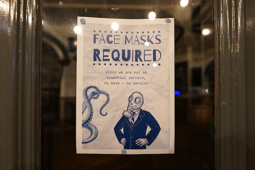 A sign on a door telling people they must wear a face mask.