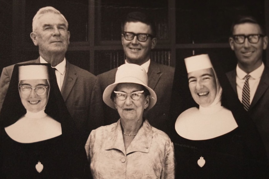 A black and white photo of two nuns, a woman and three men