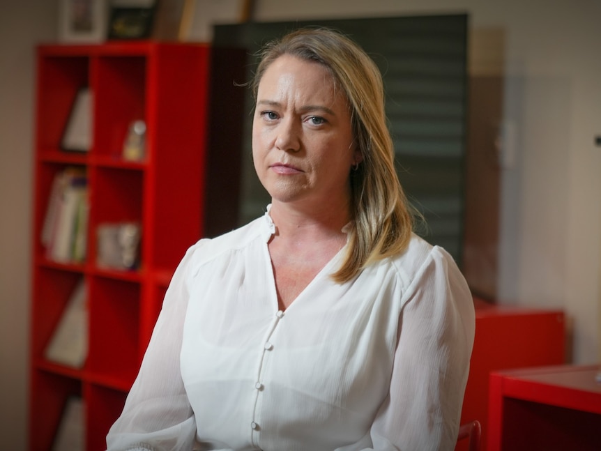 Amy, a woman with blonde hair, looks serious in a portrait.