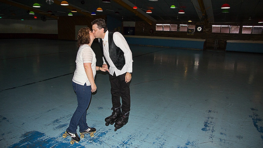 A couple share a kiss on a roller skating rink