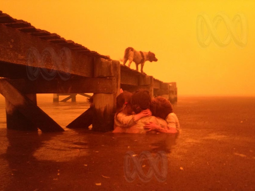 Families huddle in the water next to a jetty during a bushfire sweeping through Dunalley.