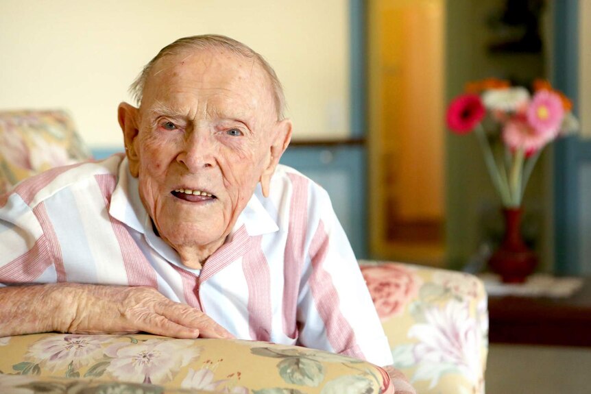 101 year old Ted Broadhurst sits in a lounge chair looking at the camera