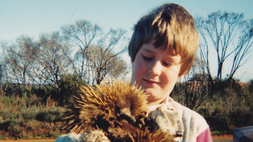 A young boy holding an echidna