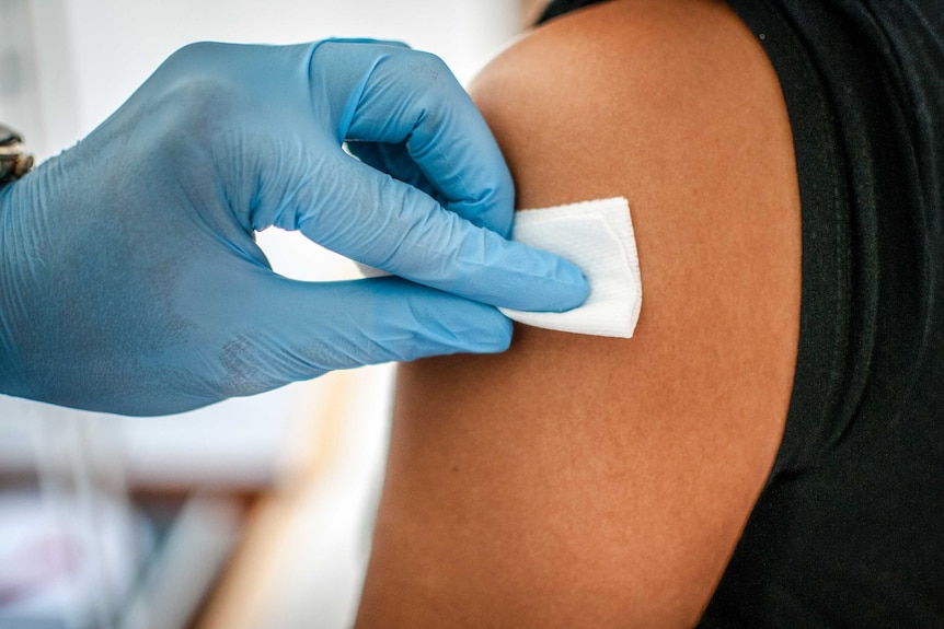 Doctor disinfects skin of patient before vaccination.