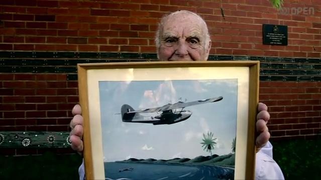 Old man holds framed photo of war plane