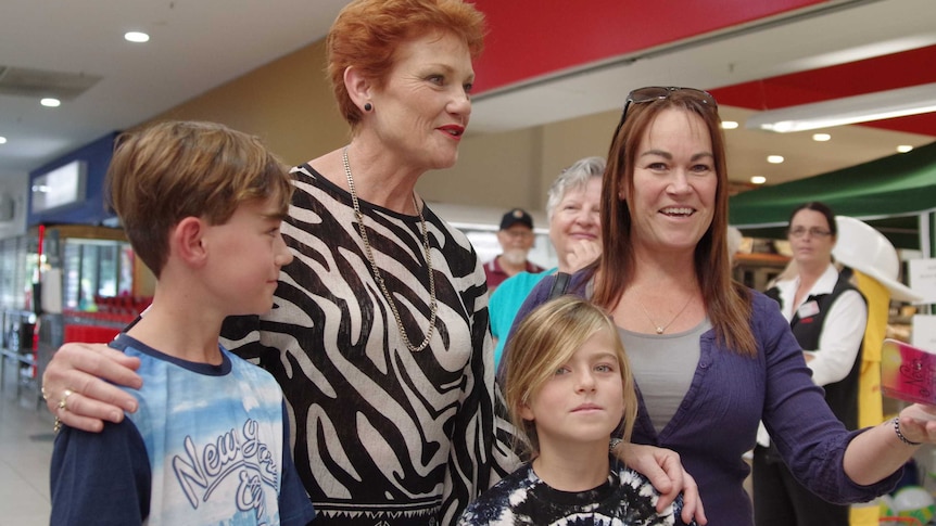 Pauline Hanson poses for a photo  with a woman and two children in a shopping centre.