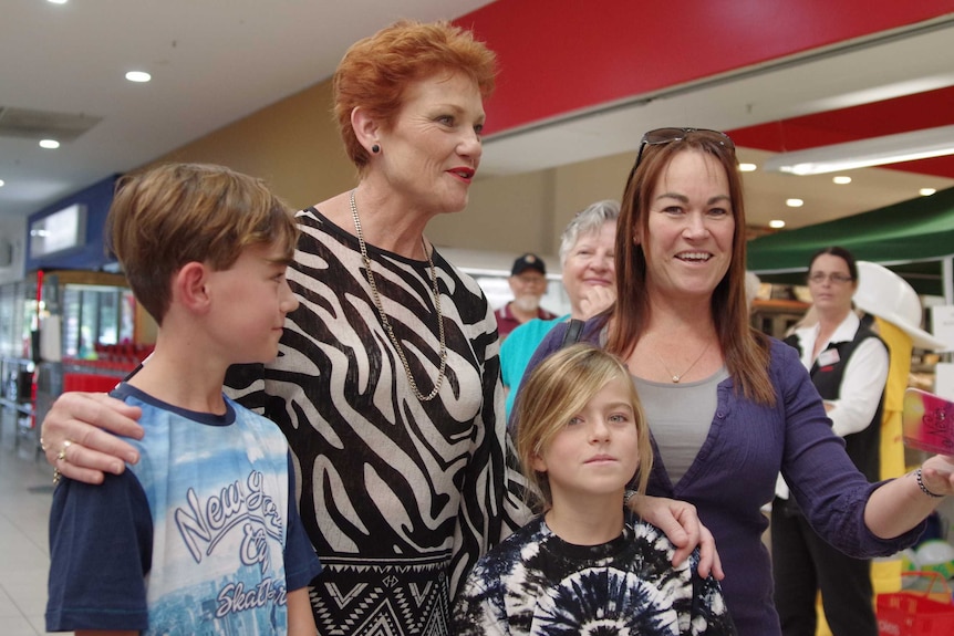 Pauline Hanson poses for a photo  with a woman and two children in a shopping centre.