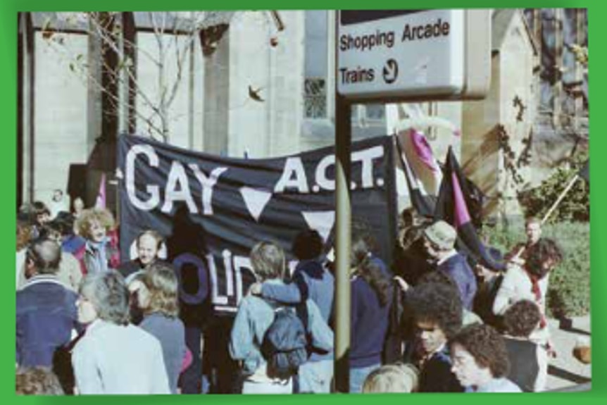 A group of people holding up a banner that says "GAY ACT". 