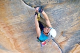 a woman rock climbs up a rock face