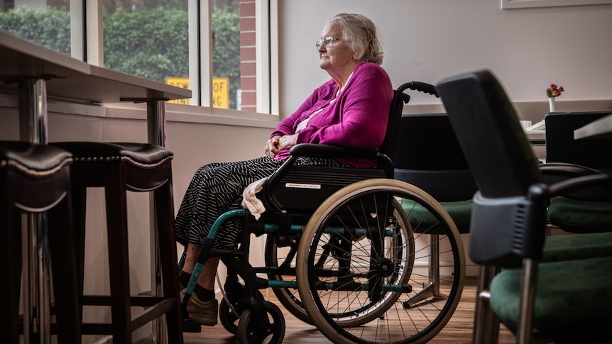Dorothy Major looks out the window at her aged care home. She sits in a wheelchair.