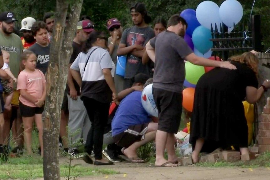 People gather at the side of the road comforting one another