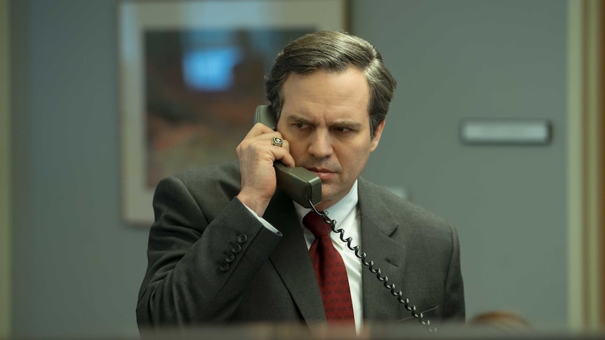 The actor Mark Ruffalo with gray hair and gray suit on the phone looking concerned in the film Dark Waters