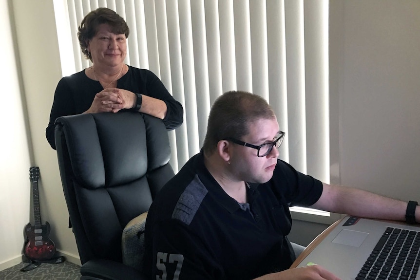 Nathan Hardy sits at his laptop as mum Leah looks on