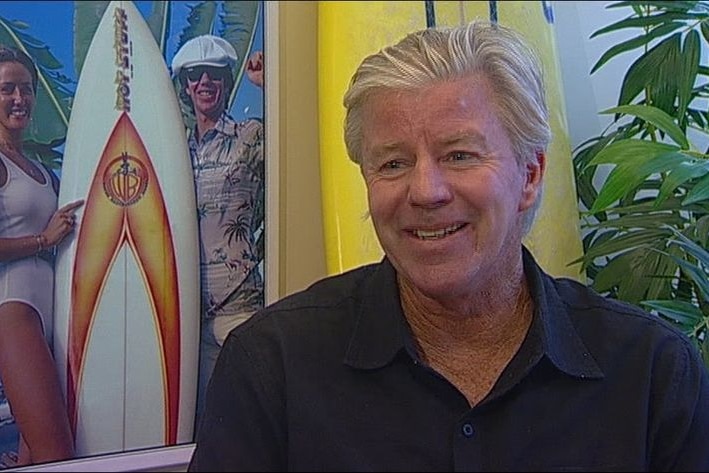A man with grey hair smiles while being interviewed.