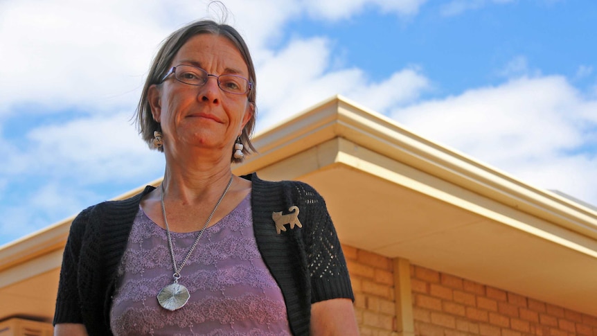 Rowena Skinner looking down into the camera in front of her house.