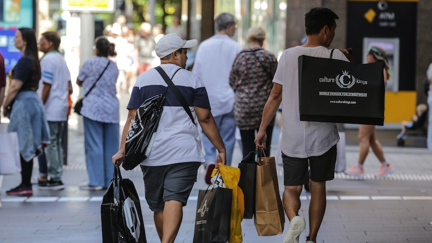 Two young men carry shopping bags in the city street