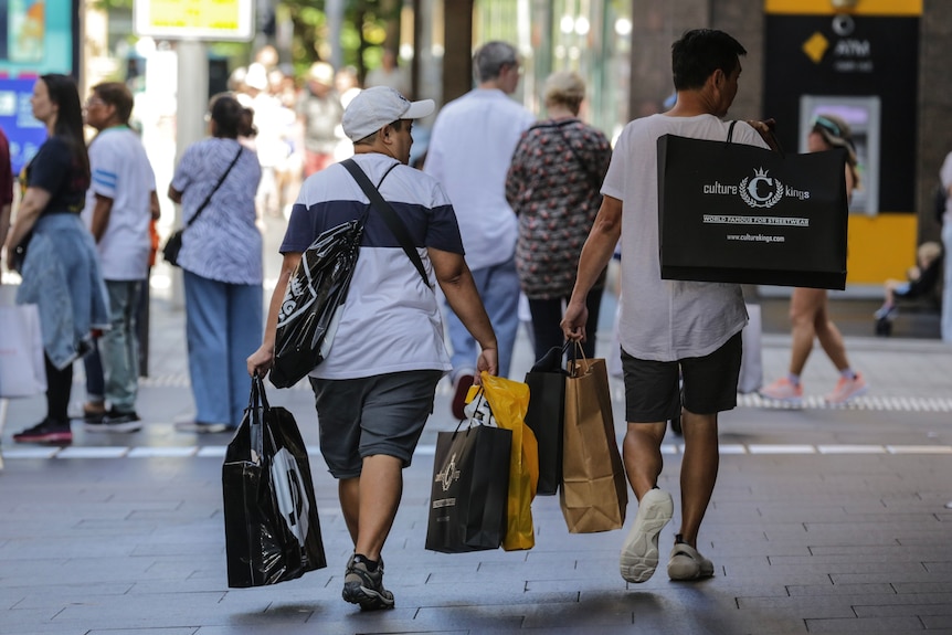 Two young men carry shopping bags in the city street