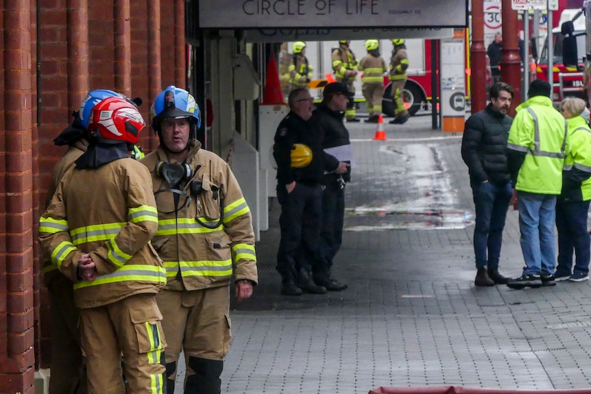 Two firemen standing on the street.