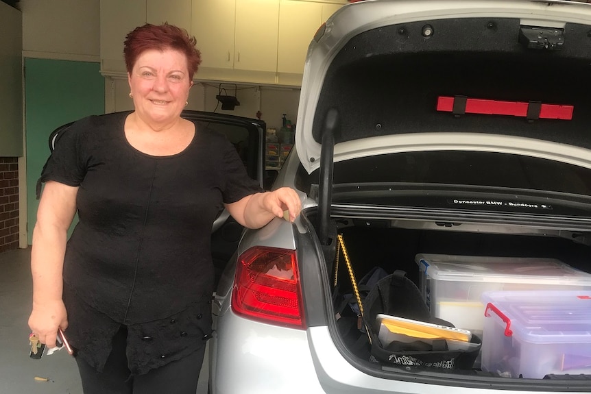 Bambi Butera stands next to the open boot of her car, packed with boxes of photos as she prepares to leave Bundoora.