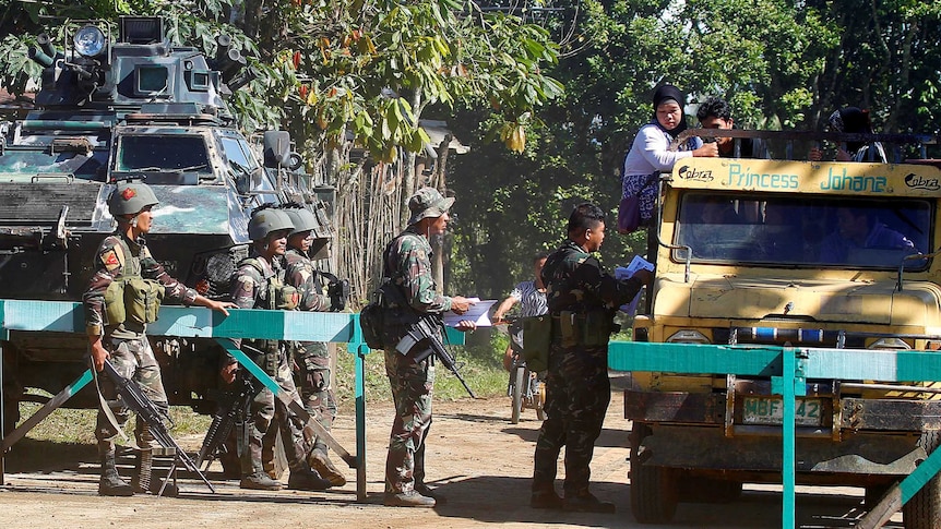 Soldiers distribute pictures of a member of extremist group Abu Sayyaf Isnilon Hapilon.