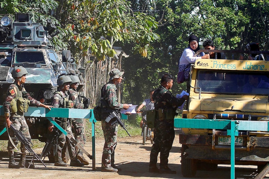 Soldiers distribute pictures of a member of extremist group Abu Sayyaf Isnilon Hapilon.