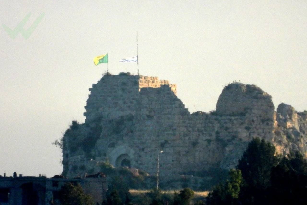 Dos banderas sobre un castillo medieval.