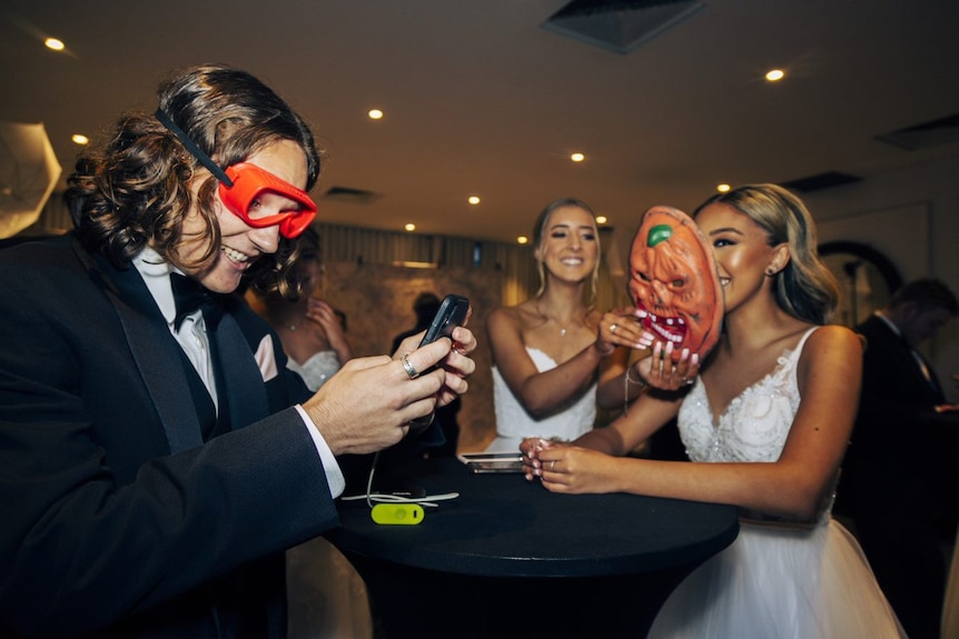 Reid Burgoyne wears novelty red sunglasses and laughs with Gemma and a friend