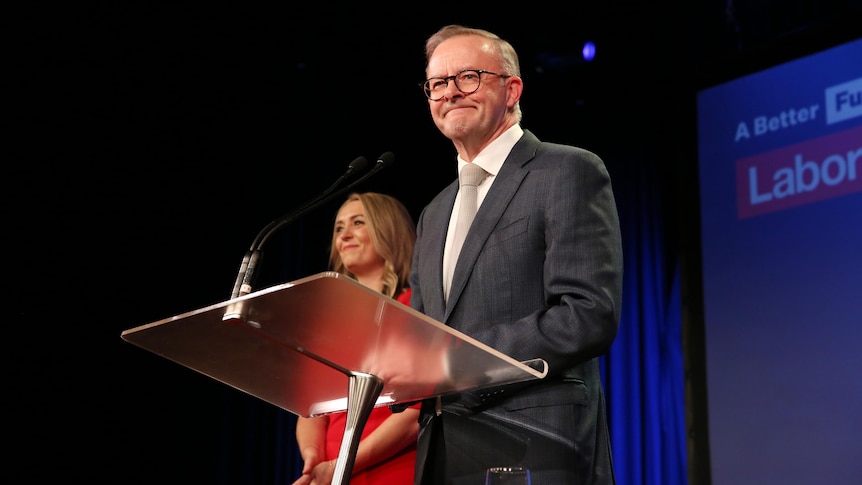 Anthony Albanese standing at a lectern with a woman next to him