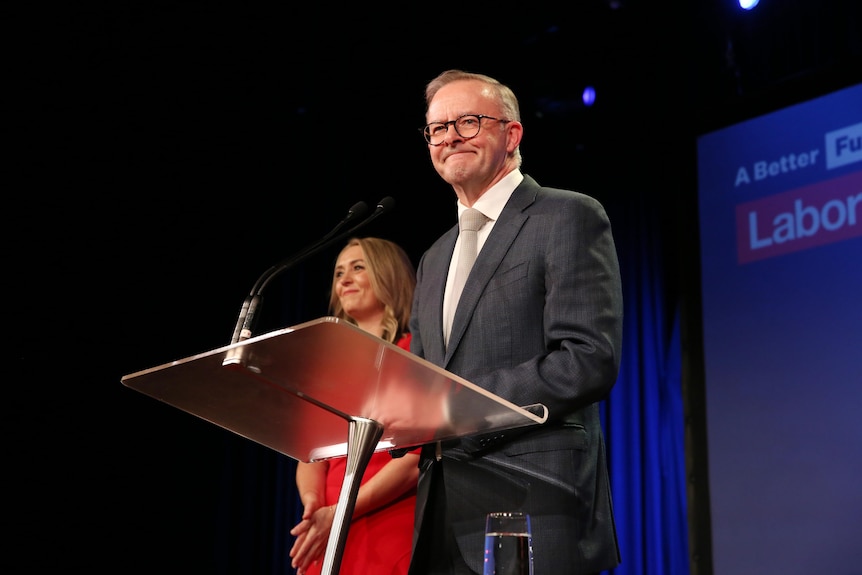 Anthony Albanese standing at a lectern with a woman next to him