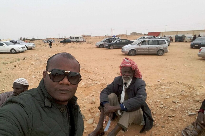 Mr Nasr with his father sit in the sand