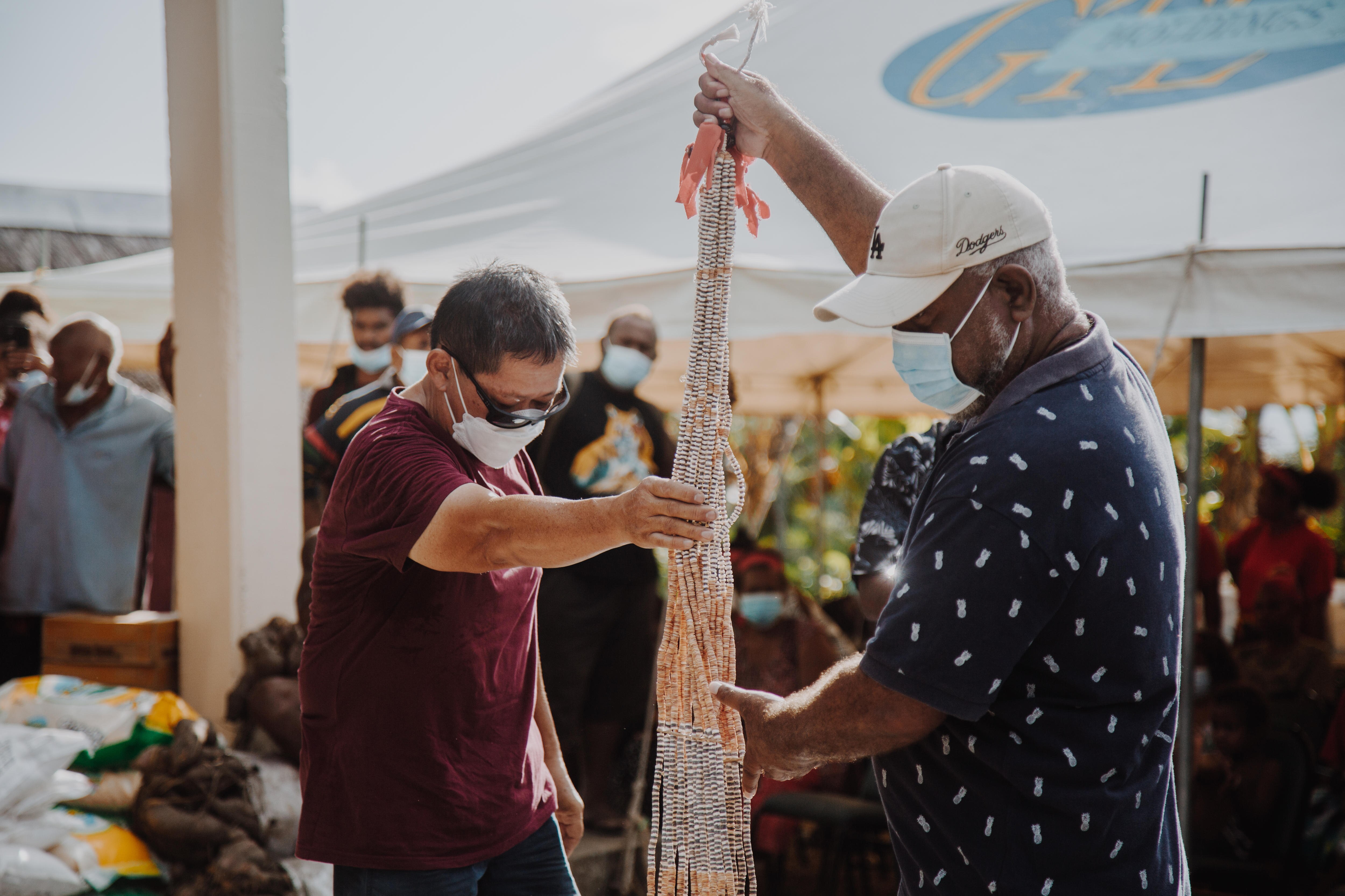 Groom's father passing on the shell money to bride's father at a bride price ceremony.