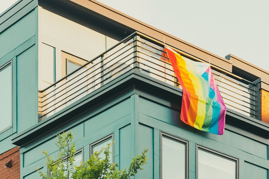 building with rainbow pride flag draped over balcony