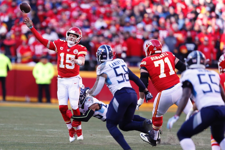 An NFL quarterback throws the ball as a defender tries to grab him around the leg.