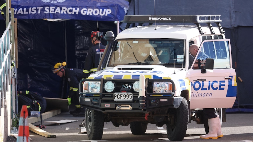 A police 4x4 is parked in front of a crime scene and firefighters and police examine the area